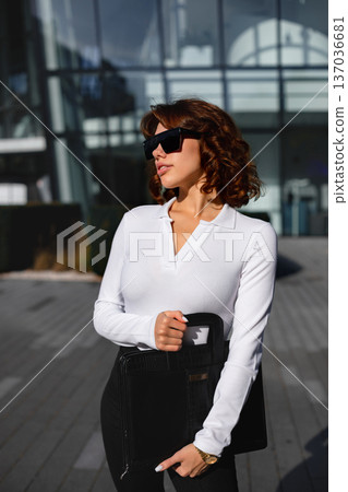 Professional businesswoman holding leather briefcase walking in city 137036681