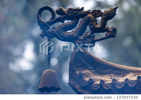 Rustic dragon roof ornament with hanging bell in misty forest Rustic dragon roof ornament with hanging bell in misty forest 137037330