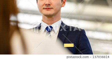 The serious expression of a businessman serving customers ■Photography cooperation: Kansai International Airport (KIX) The serious expression of a businessman serving customers ■Photography cooperation: Kansai International Airport (KIX) 137038814