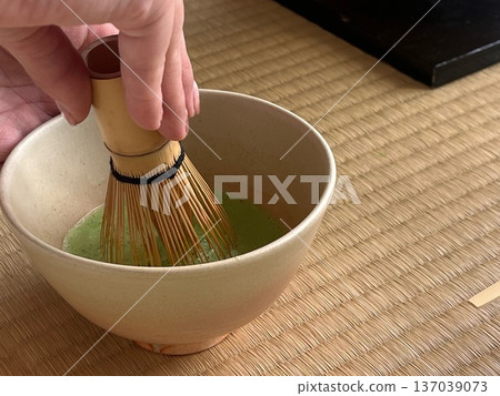 一位茶藝師在日式房間用茶碗準備抹茶。 一位茶藝師在日式房間用茶碗準備抹茶。 137039073