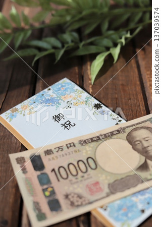 A light blue, floral gift envelope and a new 10,000 yen bill. A gift for graduation or graduation celebration. A light blue, floral gift envelope and a new 10,000 yen bill. A gift for graduation or graduation celebration. 137039574