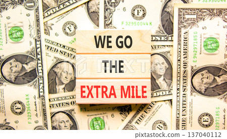 Support, help we go the extra mile symbol. Concept words We go the extra mile on beautiful wooden blocks. Beautiful dollar bills background. Business we go the extra mile concept. Copy space. Support, help we go the extra mile symbol. Concept words We go the extra mile on beautiful wooden blocks. Beautiful dollar bills background. Business we go the extra mile concept. Copy space. 137040112