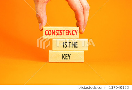 Consistency is the key symbol. Concept words Consistency is the key on beautiful wooden blocks. Beautiful orange background. Businessman's hand. Business consistency is the key concept. Copy space. Consistency is the key symbol. Concept words Consistency is the key on beautiful wooden blocks. Beautiful orange background. Businessman's hand. Business consistency is the key concept. Copy space. 137040133