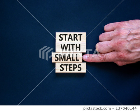 Start with small steps symbol. Concept words phrase Start with small steps on beautiful wooden blocks. Beautiful black background. Businessman hand. Business Start with small steps concept. Copy space Start with small steps symbol. Concept words phrase Start with small steps on beautiful wooden blocks. Beautiful black background. Businessman hand. Business Start with small steps concept. Copy space 137040144