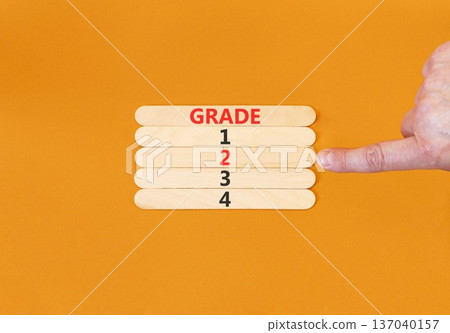 Time to grade 2 symbol. Concept word Grade 1 2 3 4 on beautiful wooden sticks. Businessman's hand. Beautiful orange background. Business planning and time to grade 2 concept. Copy space. Time to grade 2 symbol. Concept word Grade 1 2 3 4 on beautiful wooden sticks. Businessman's hand. Beautiful orange background. Business planning and time to grade 2 concept. Copy space. 137040157