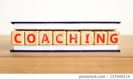 Coaching word symbol. Concept word Coaching on beautiful wooden blocks in beautiful book. Beautiful wooden table white background. Business support help coaching word concept. Copy space. 137040214