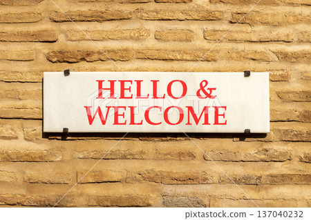 Hello and welcome symbol. Concept words Hello and welcome on beautiful big white sign plate. Beautiful old brown brick wall background. Business hello and welcome concept. Copy space. 137040232