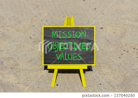 Mission objectives values symbol. Concept words Mission Objectives Values on beautiful black yellow blackboard. Beautiful sand beach background. Business mission objectives values concept. Copy space. 137040280