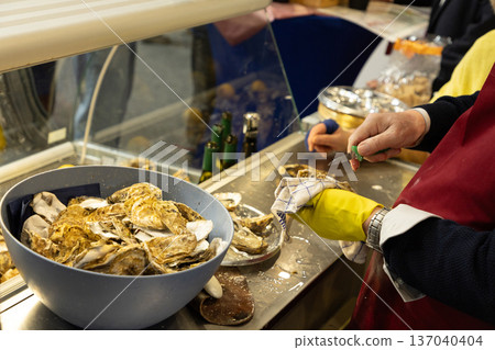 Chef preparing fresh oysters in kitchen with vibrant seafood display Chef preparing fresh oysters in kitchen with vibrant seafood display 137040404