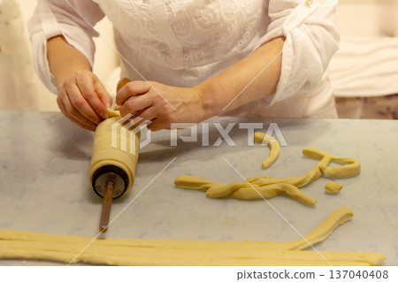 Woman preparing dough with hands on rolling pin in kitchen setting 137040408