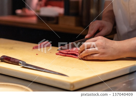 Chef slicing fresh fish on wooden cutting board in professional kitchen Chef slicing fresh fish on wooden cutting board in professional kitchen 137040409