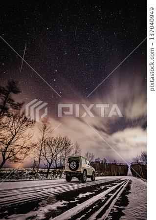 An off-road vehicle on a snowy road and the Milky Way A winter night sky with shooting stars An off-road vehicle on a snowy road and the Milky Way A winter night sky with shooting stars 137040949