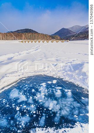 Air bubbles trapped in the ice and the Taushubetsu River Bridge - a fantastic winter scene Air bubbles trapped in the ice and the Taushubetsu River Bridge - a fantastic winter scene 137040966