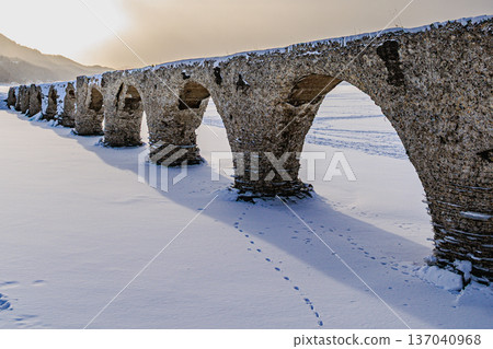 Snow-covered Lake Nukabira and the Taushubetsu River Bridge under a blue sky 137040968