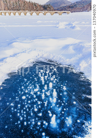Ice bubbles on Lake Nukabira and the Taushubetsu River Bridge: A spectacular winter view (Kamishihoro, Hokkaido) Ice bubbles on Lake Nukabira and the Taushubetsu River Bridge: A spectacular winter view (Kamishihoro, Hokkaido) 137040970