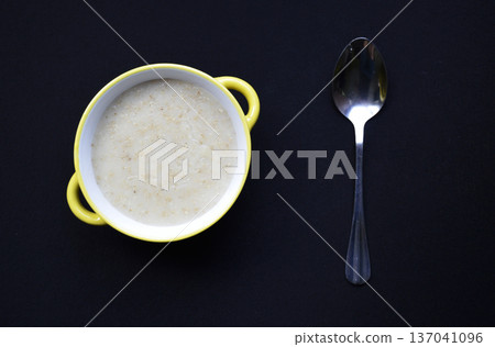 bowl with oatmeal cooked in milk and spoon on a black background bowl with oatmeal cooked in milk and spoon on a black background 137041096