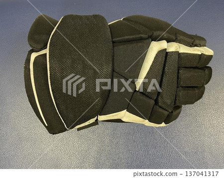 a hockey glove on the floor in a sports locker room a hockey glove on the floor in a sports locker room 137041317