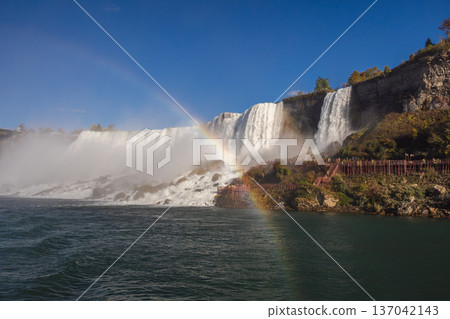 Niagara Falls waterfall with rainbow and observation walkway in misty landscape Niagara Falls waterfall with rainbow and observation walkway in misty landscape 137042143