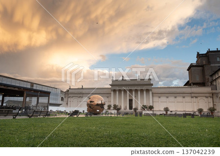 An evening view within the Vatican City, showing the gardens and architecture near the Vatican Museums. The scene evokes the atmosphere leading to the Sistine Chapel. 137042239
