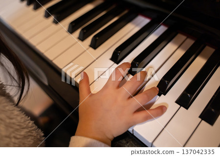 Children's hand playing the piano Children's hand playing the piano 137042335