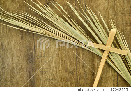 Palm sunday cross and palm branches on wood surface Palm sunday cross and palm branches on wood surface 137042355