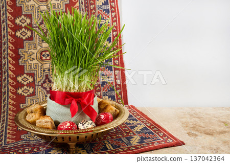 Nowruz haft-sin sabzeh, painted eggs, and baklava on carpet 137042364