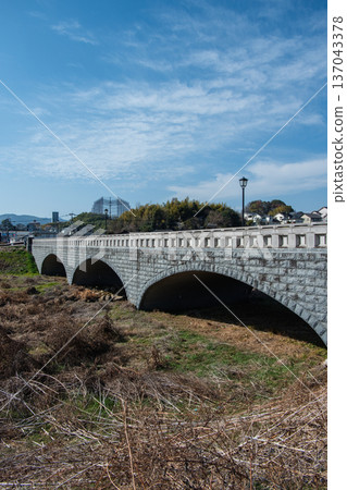 An arch bridge over a landscape of blue sky and white clouds An arch bridge over a landscape of blue sky and white clouds 137043378