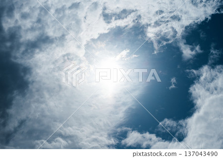 The sun shining in the center of the blue sky and flowing white clouds The sun shining in the center of the blue sky and flowing white clouds 137043490