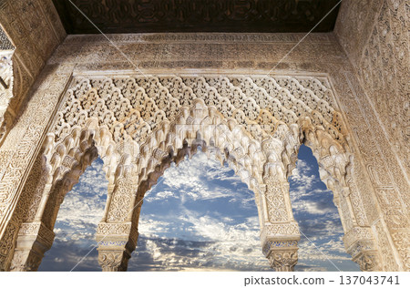 Arches in Islamic (Moorish) style (against the background of a beautiful sky with clouds) in Alhambra, Granada, Spain Arches in Islamic (Moorish) style (against the background of a beautiful sky with clouds) in Alhambra, Granada, Spain 137043741