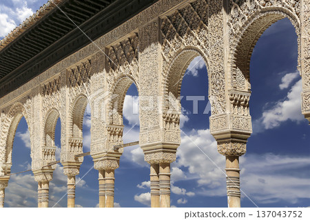Arches in Islamic (Moorish) style (against the background of a beautiful sky with clouds) in Alhambra, Granada, Spain 137043752