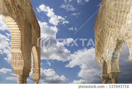 Arches in Islamic (Moorish) style (against the background of a beautiful sky with clouds) in Alhambra, Granada, Spain Arches in Islamic (Moorish) style (against the background of a beautiful sky with clouds) in Alhambra, Granada, Spain 137043758