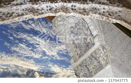 Arches in Islamic (Moorish) style (against the background of a beautiful sky with clouds) in Alhambra, Granada, Spain Arches in Islamic (Moorish) style (against the background of a beautiful sky with clouds) in Alhambra, Granada, Spain 137043775