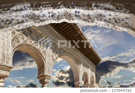 Arches in Islamic (Moorish) style (against the background of a beautiful sky with clouds) in Alhambra, Granada, Spain Arches in Islamic (Moorish) style (against the background of a beautiful sky with clouds) in Alhambra, Granada, Spain 137043782