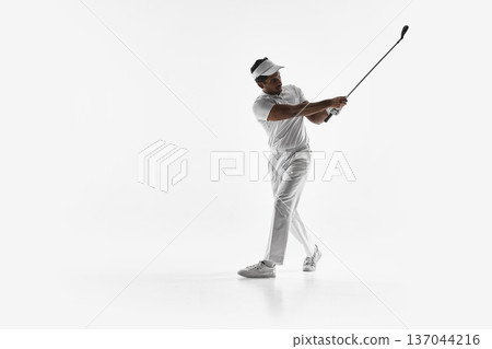 Golfer mid follow through stepping forward after drive on white background. Golfer mid follow through stepping forward after drive on white background. 137044216