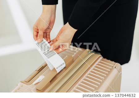 The hands of a female airport ground staff member attaching a tag to a carry-on bag (Photo courtesy of Kansai International Airport (KIX)) The hands of a female airport ground staff member attaching a tag to a carry-on bag (Photo courtesy of Kansai International Airport (KIX)) 137044632