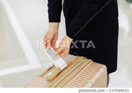 一名機場地勤女工作人員正在為隨身行李貼標籤。 (照片由關西國際機場(KIX)提供) 一名機場地勤女工作人員正在為隨身行李貼標籤。 (照片由關西國際機場(KIX)提供) 137044633