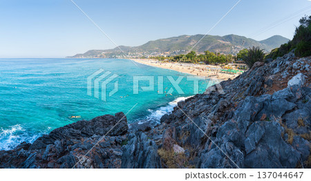 Awesome panoramic view on sea coast and mountains. Tourists beach in Turkey, Alanya. Clear sunny day with rocky beach and seaside and turquoise water Awesome panoramic view on sea coast and mountains. Tourists beach in Turkey, Alanya. Clear sunny day with rocky beach and seaside and turquoise water 137044647