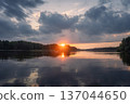 Lake and sunset landscape. Amazing nature view. Clouds and son on horizon over lake with reflections at water surface. 137044650