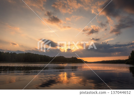Amazing landscape of lake at colourful sunset with gold clouds as mirror on the surface of water with awasome reflections Amazing landscape of lake at colourful sunset with gold clouds as mirror on the surface of water with awasome reflections 137044652