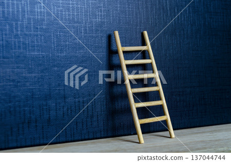 Wooden ladder leaning on deep blue cover with customizable space for text or ideas Wooden ladder leaning on deep blue cover with customizable space for text or ideas 137044744