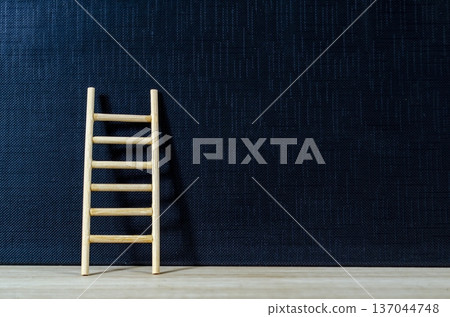 Wooden ladder leaning on deep blue backdrop with customizable space for text or ideas, representing ambition and success journey concept 137044748