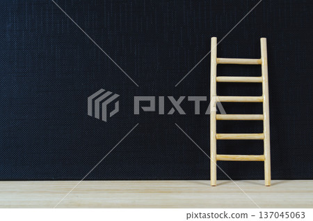 Wooden ladder leaning on deep dark cover with customizable space for text or ideas. 137045063