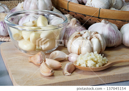 Close-up shot of minced garlic in wooden spoon placed on wooden chopping board In the kitchen prepared for food ingredients. 137045154