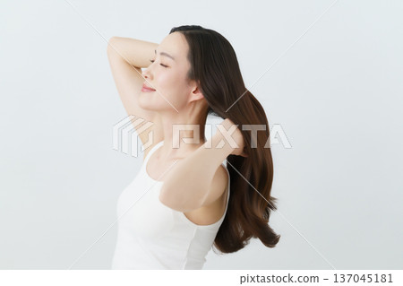 一位年輕的日本女子正在梳理她向後垂落的長髮，美極了。 137045181