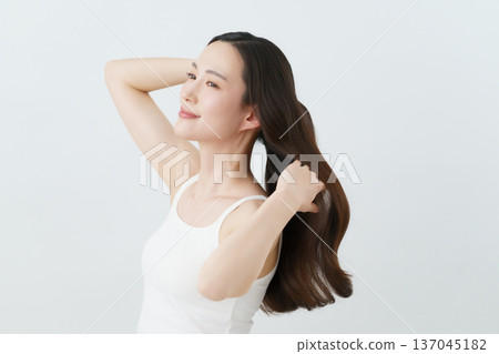 A young Japanese woman brushing her long hair back Beauty A young Japanese woman brushing her long hair back Beauty 137045182