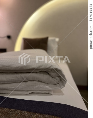 Comfortable hotel room bed with neatly folded white linens and soft brown pillow background 137045313