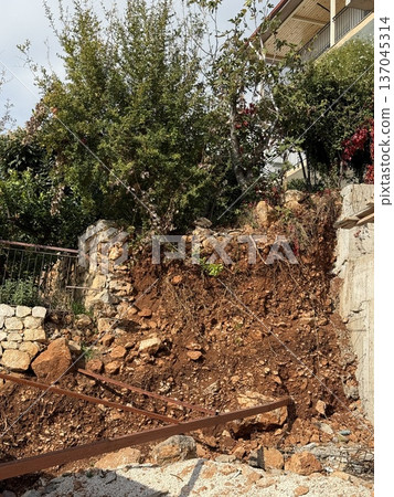 Landslide site with exposed soil and uprooted trees on a construction site Landslide site with exposed soil and uprooted trees on a construction site 137045314