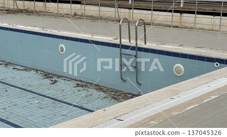 Empty swimming pool with metal ladder, abandoned and neglected, perfect for background Empty swimming pool with metal ladder, abandoned and neglected, perfect for background 137045326