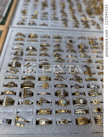 Assorted gold rings on display in jewelry shop, with various designs and gemstones for sale 137045333