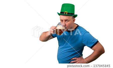 Man wearing green leprechaun hat and drinking beer from glass. St. Patricks Day festive character posing with pint. Irish holiday celebration and fun tradition. photography Man wearing green leprechaun hat and drinking beer from glass. St. Patricks Day festive character posing with pint. Irish holiday celebration and fun tradition. photography 137045845